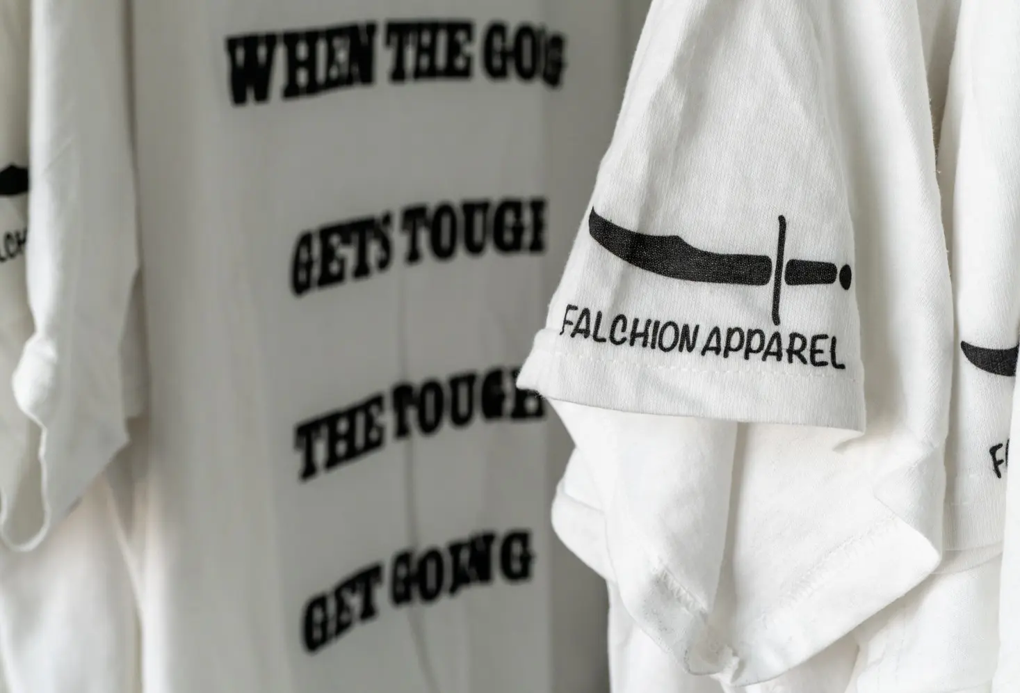 Close-up of a white shirt with motivational text and sleeve branding.
