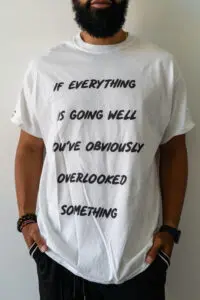 Person wearing a white t-shirt with a motivational quote about overlooked details.