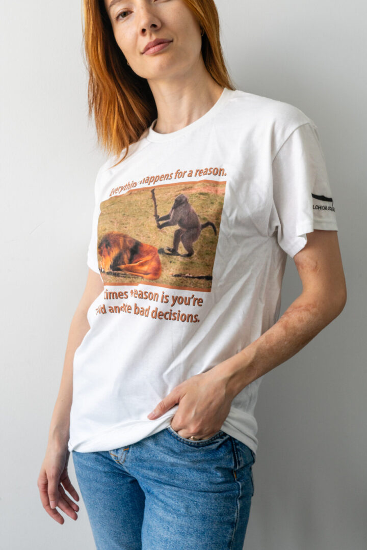 Person wearing a white graphic T-shirt with a dinosaur design.