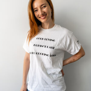 Smiling woman in white t-shirt with black text against a plain white background.