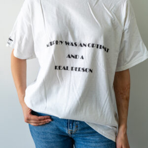 Person wearing a white T-shirt with text and blue jeans.