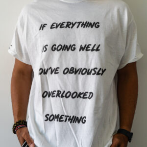 Person wearing a white t-shirt with a motivational quote about overlooked details.