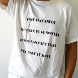 Person wearing a white T-shirt with black text printed on it.