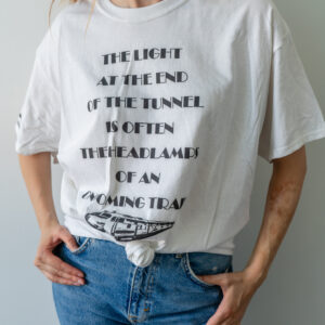 Person wearing a white t-shirt with black text and blue jeans.